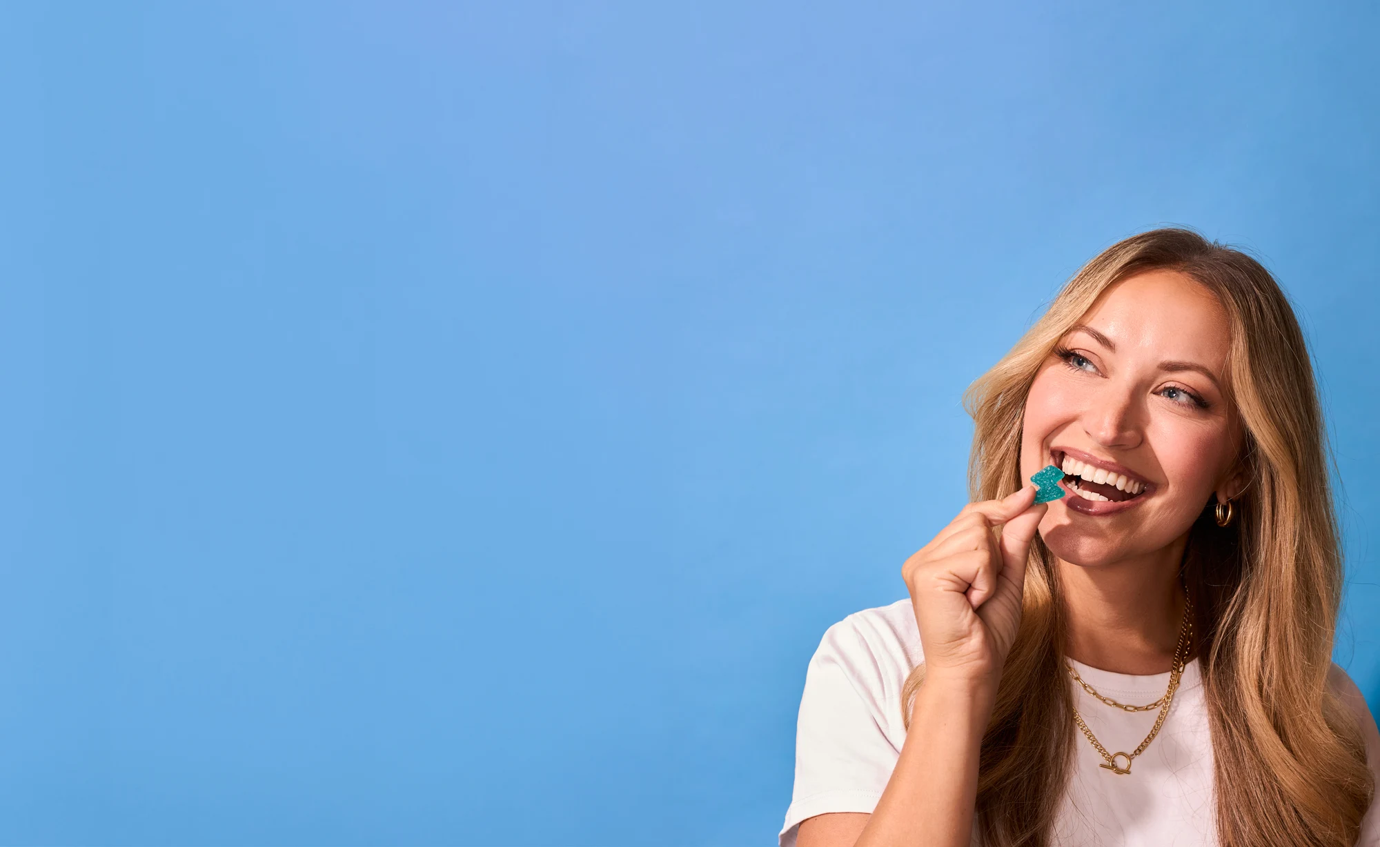 Smiling woman biting a blue FocusFuel caffeine gummy